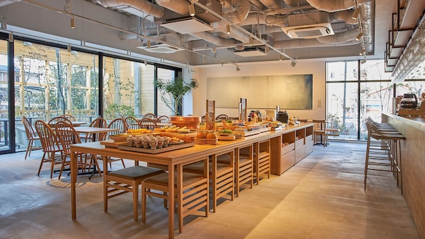 Un amplio comedor con mesas y sillas de madera, una disposición tipo buffet y grandes ventanales con vistas al exterior.