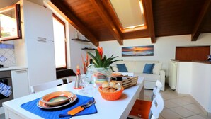 A dining area with a white table, blue placemat, plates, cutlery, and a basket of bread.