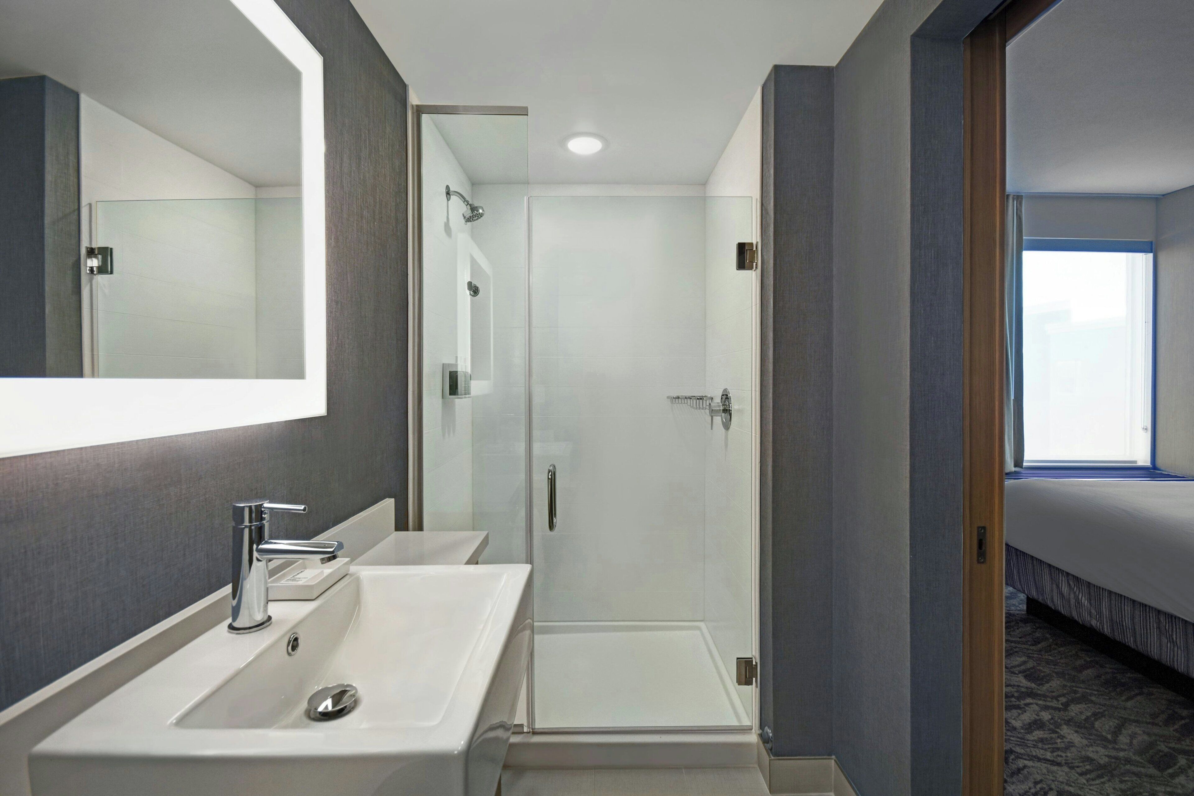 A modern bathroom with two sinks, a shower, and a large mirror.