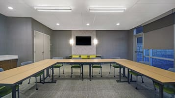 A conference room with a long table, chairs, a flat-screen TV, and a stone-patterned wall.