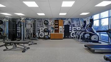 A gym with various exercise equipment, a clock, and a water dispenser.