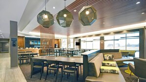 A modern hotel lobby with a central seating area, a reception desk, and large windows offering a view of the outdoors. - SpringHill Suites by Marriott St. Paul Arden Hills (Arden Hills)