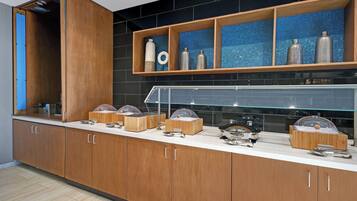 Una cocina moderna con armarios de madera, una encimera con diversos electrodomésticos y una vitrina de vidrio.