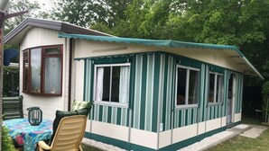 A small, single-story house with a green-striped exterior and a covered porch. - 5-Star Park Texel (De Cocksdorp)