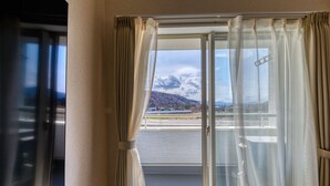 A room with a large sliding glass door leading to a balcony with a mountain view. - Bon Moment B (Fujikawaguchiko)