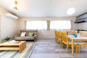 A modern living room with a sofa, coffee table, and dining area with chairs and a table. - Bon Moment B (Fujikawaguchiko)