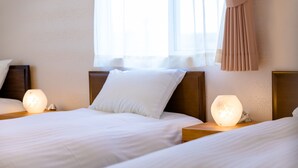 A hotel room with two beds, each with a bedside lamp and a pillow. - Bon Moment B (Fujikawaguchiko)