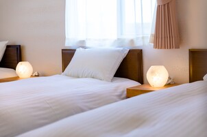 Quarto de hotel com duas camas, cada uma com uma luminária e um travesseiro.
