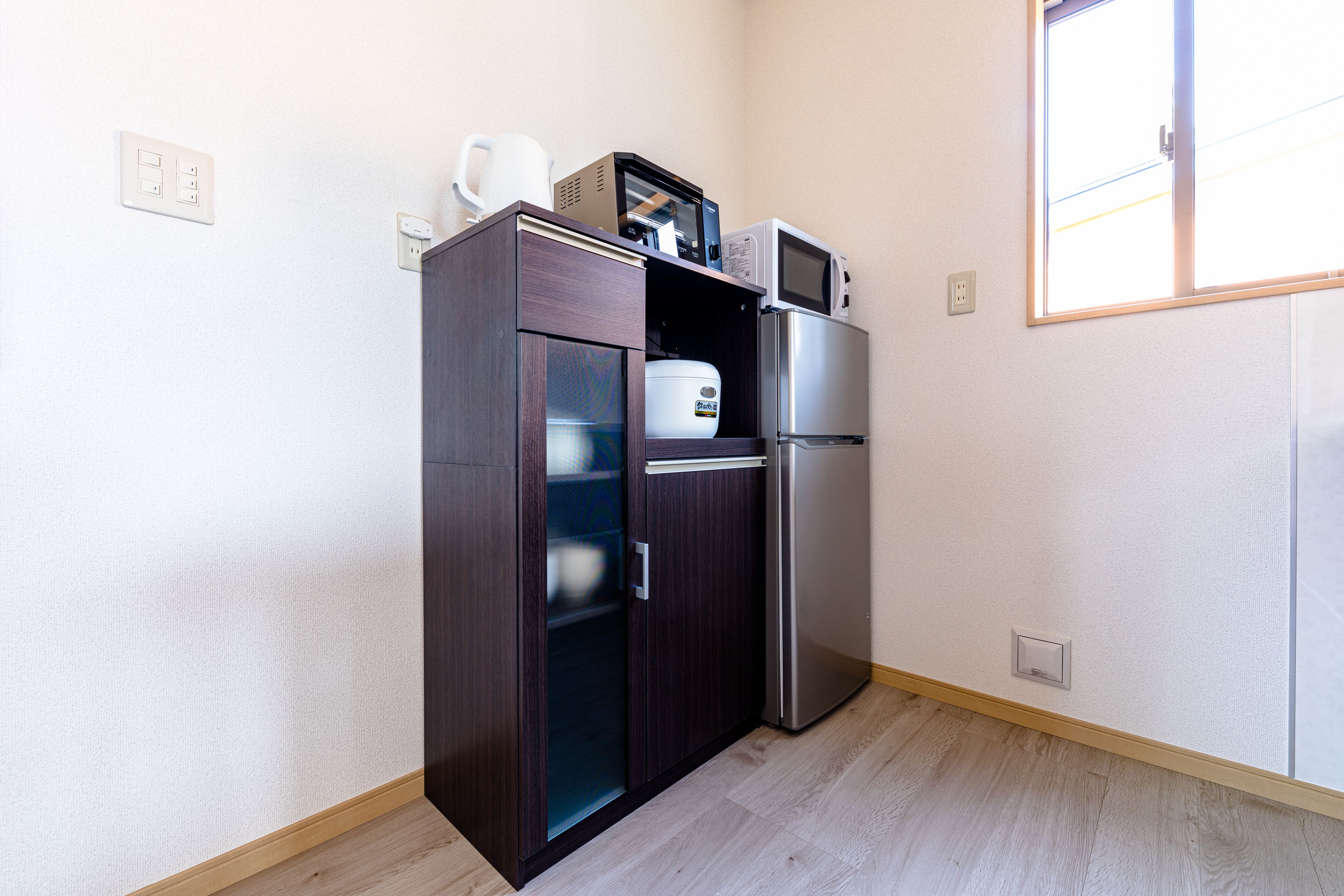 A compact kitchen with a refrigerator, microwave, and a cabinet with a coffee maker.
