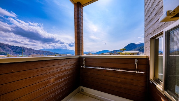 Un balcon en bois offrant une vue sur les montagnes et un ciel dégagé.
