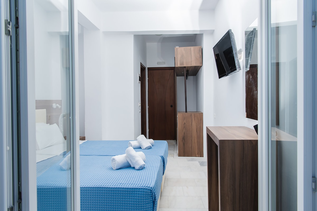 A modern hotel room with two beds, a TV, and a wooden cabinet.