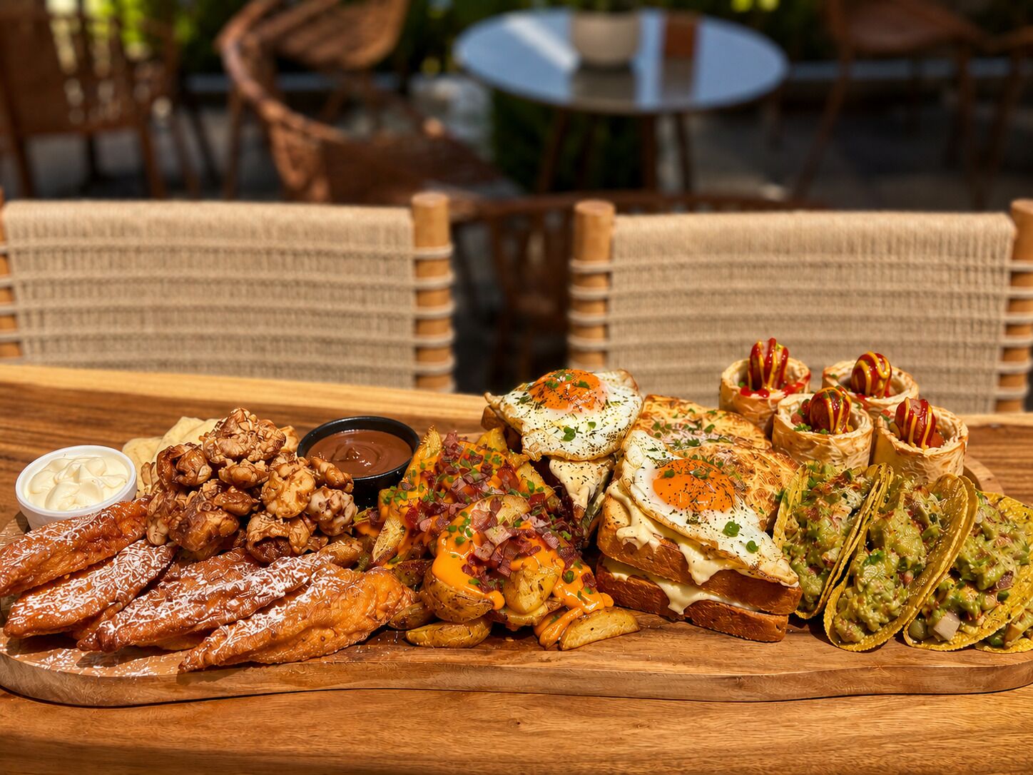 A wooden table with a variety of food items including pastries, potatoes, and a bowl of dipping sauce.