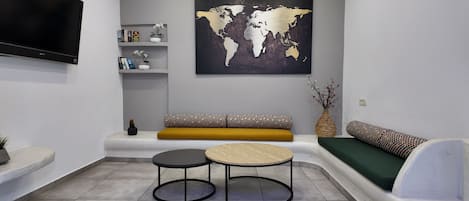 Ein modernes Wohnzimmer mit einer Couch, zwei runden Tischen, einer Weltkarte als Wandbild und einem Fernseher.
