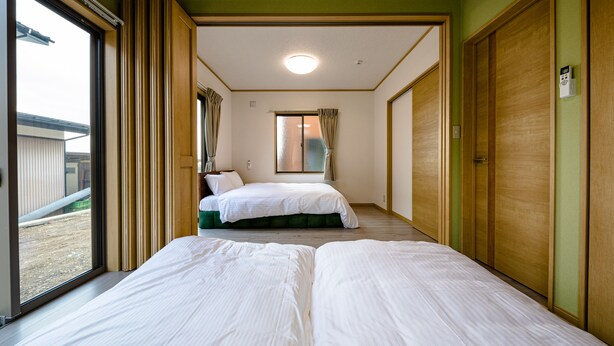 Habitación de hotel con dos camas, un ventanal grande y una puerta corredera.