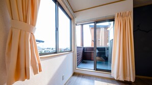 Una habitación con ventanas amplias, vista a un edificio y puerta corrediza al exterior.