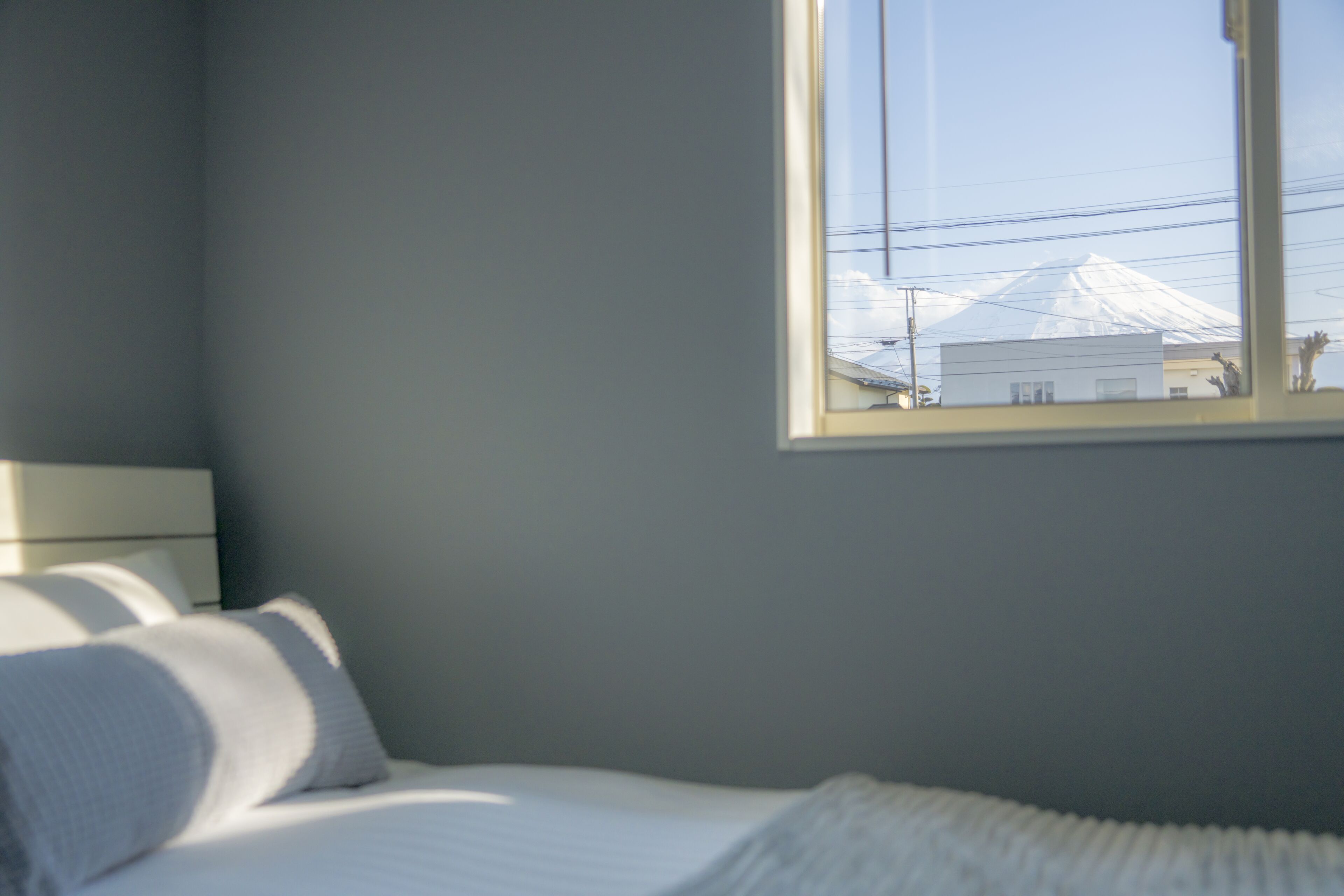 A bedroom with a bed, pillows, a nightstand, and a window overlooking a snowy mountain.