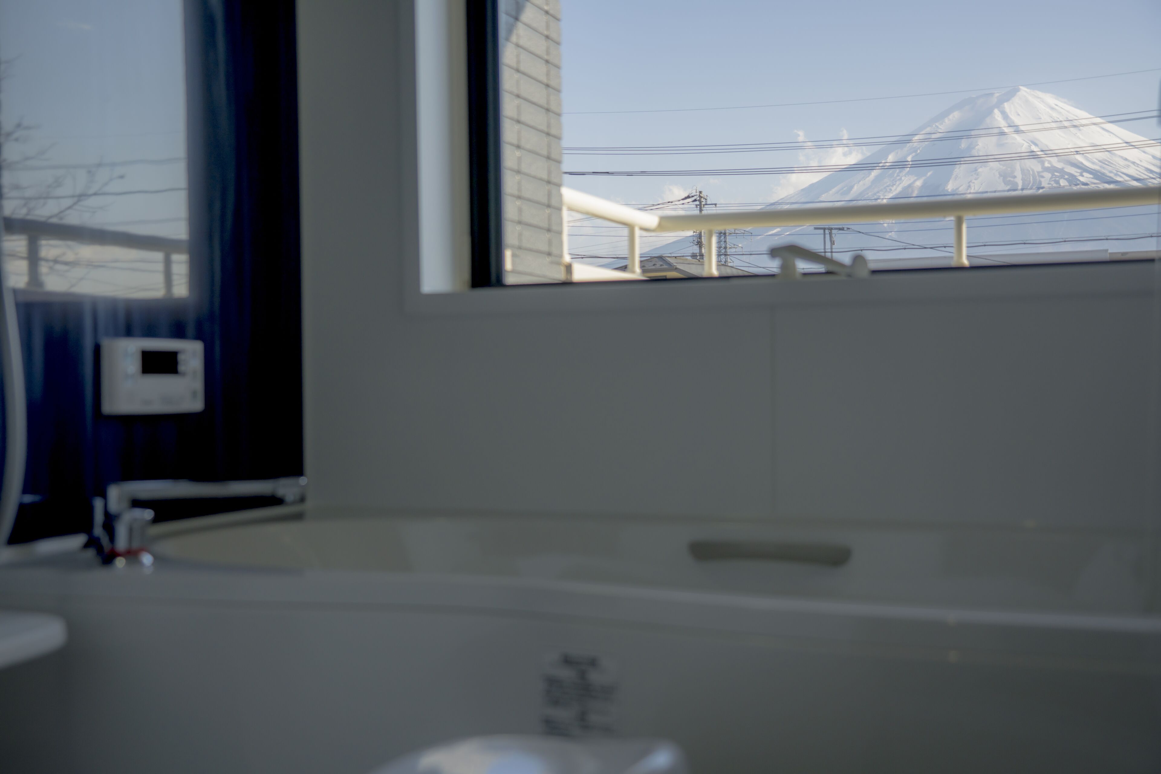 A bathroom with a bathtub, a window, and a view of a snow-capped mountain.