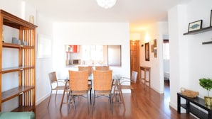 Un interno moderno con zona pranzo, mensole in legno e cucina sullo sfondo.