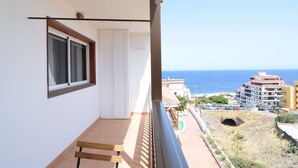 Un balcone con vista sul mare, una porta e una finestra.
