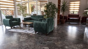A spacious lounge area with a green sofa set, a coffee table, and potted plants. - Side Spring Hotel (Manavgat)