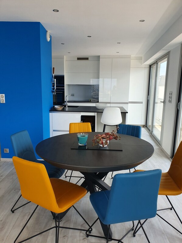 Une cuisine moderne avec des armoires blanches, un comptoir noir et un mur bleu.