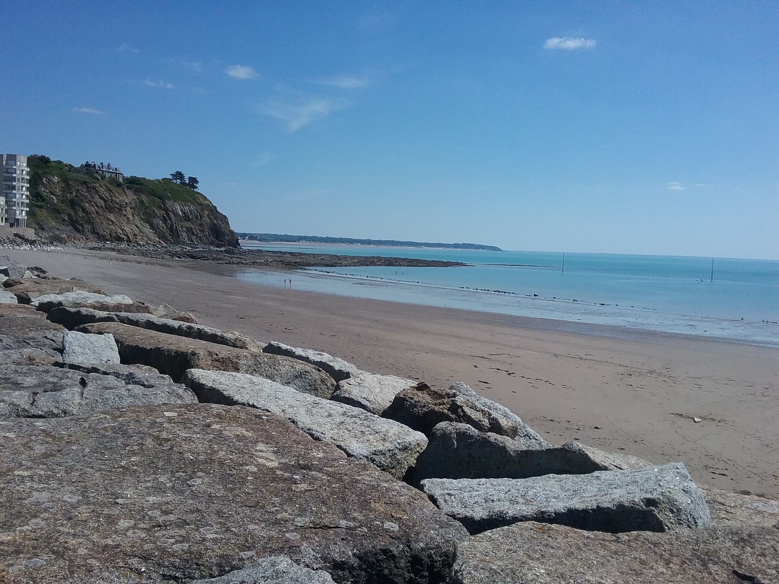 A rocky beach with a clear view of the sea and a distant coastline.