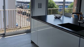 A modern kitchen with a large window, a balcony, and a view of the marina.