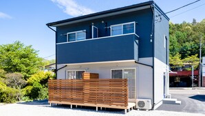 Un bâtiment à deux étages doté d’un balcon, de grandes fenêtres et d’une clôture en bois à l’avant.