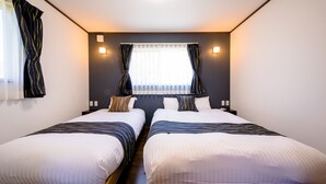 Une chambre d’hôtel avec deux lits, une fenêtre avec des rideaux et un luminaire fixé au mur.