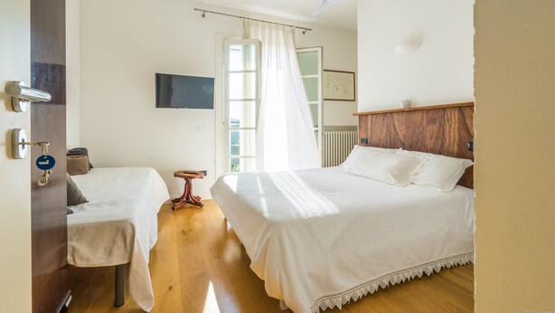 Een hotelkamer met een bed, een bureau, een stoel, een plafondventilator en een raam met gordijnen.