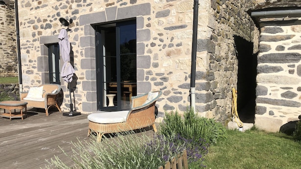 Ein Steinhaus mit einer Holzterrasse, Korbmöbeln und einem Lavendelgarten.