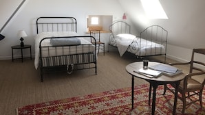 Ein Schlafzimmer mit zwei Metallbetten, einem kleinen Tisch, einem Stuhl, einer Lampe und einer Pendelleuchte.