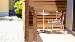 A wooden outdoor seating area with a metal table and chair, a metal pot, and a wooden bench. - Fuga-A (Fujikawaguchiko)