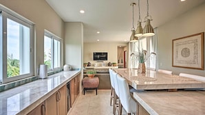 A modern kitchen with a large island, bar stools, and pendant lighting.