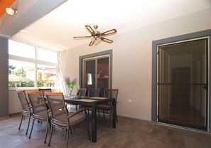 Un coin repas comprenant une table et des chaises, un ventilateur de plafond et une porte-fenêtre coulissante.