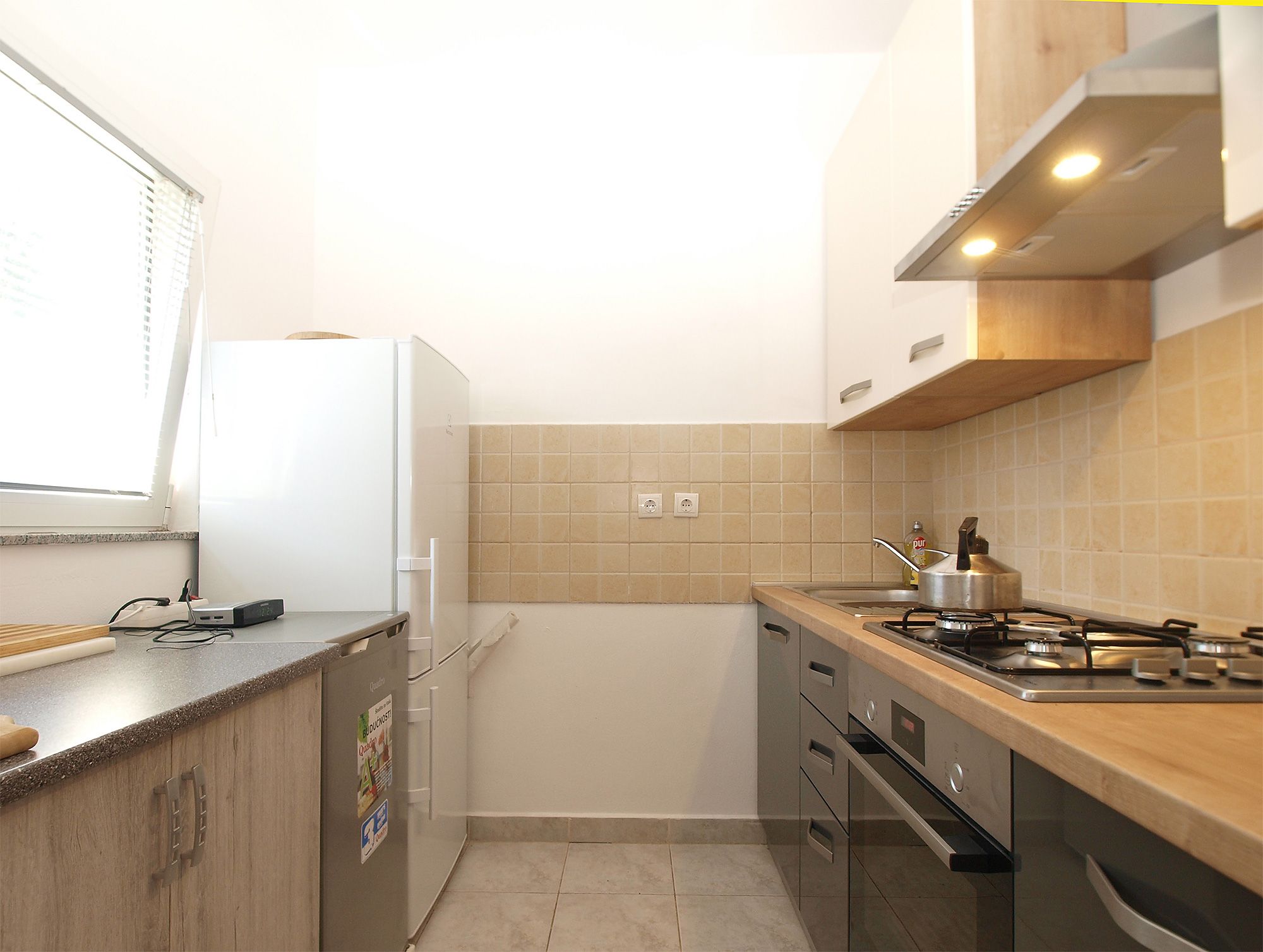 Una cocina compacta con refrigerador, estufa y gabinetes.