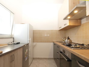 A compact kitchen with a refrigerator, stove, and cabinets. - Apartment 1975/31815 (Istria - Peroj), 200m from the beach (Peroj)