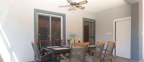 Un comedor con mesa y sillas, un ventilador de techo y una puerta.