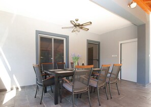 A dining area with a table and chairs, a ceiling fan, and a door.