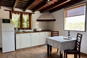 Una cocina con armarios blancos, microondas, estufa y una mesa de comedor con sillas.