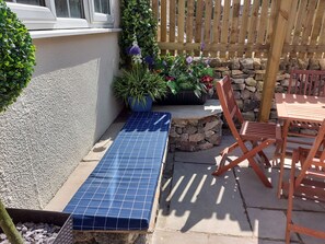A patio area with a blue tiled bench, wooden chairs, a table, and potted plants. - Lovely 4 bed House Sleeping 8 Near Ashbourne (Matlock)