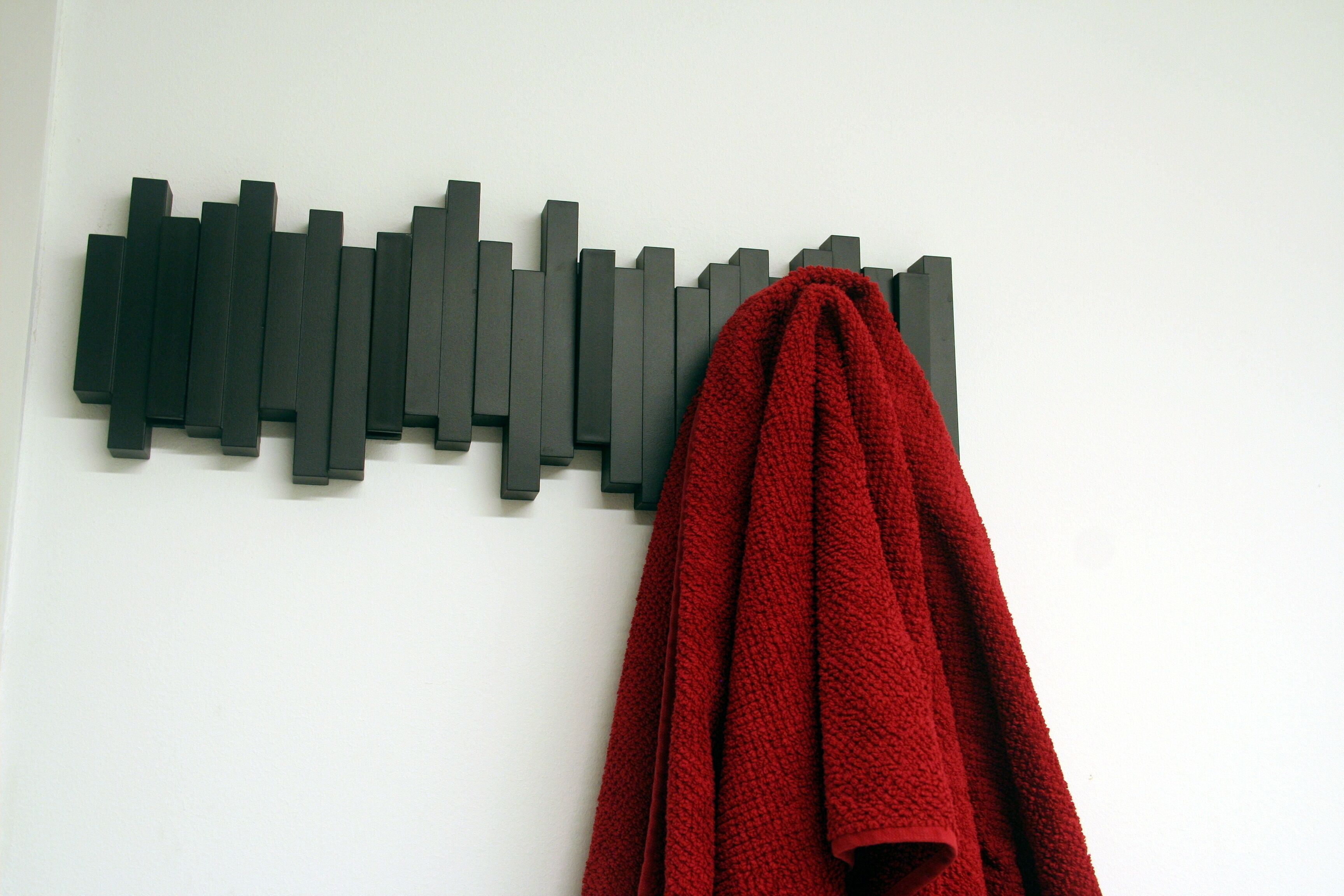 A wall-mounted abstract art piece and a red towel.
