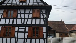 A traditional half-timbered house with multiple windows and a white picket fence.