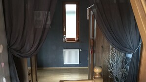 A wooden staircase with a handrail, leading to a room with a window and a radiator.