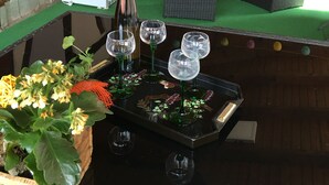 A cozy room with a sofa set, a small table with a bottle and glasses, and a decorative plant.