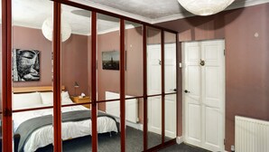 A bedroom with a bed, a nightstand, a lamp, a painting, and a wardrobe with a mirror. - Ochil Cottage In Bannockburn, Close to Stirling (Stirling)