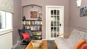 A cozy living room with a black leather chair, a grey sofa, a wooden coffee table, and a bookshelf filled with books. - Ochil Cottage In Bannockburn, Close to Stirling (Stirling)