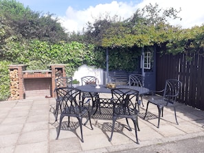 An outdoor patio with a brick fireplace, metal chairs, and a table. - Ochil Cottage In Bannockburn, Close to Stirling (Stirling)