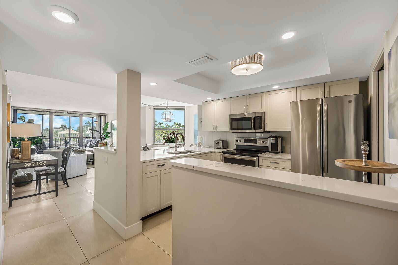 A modern kitchen with stainless steel appliances, a large island, and a dining area with a view.