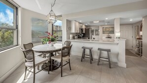 Uma cozinha moderna com uma ilha central, banquetas e uma mesa de jantar com cadeiras.